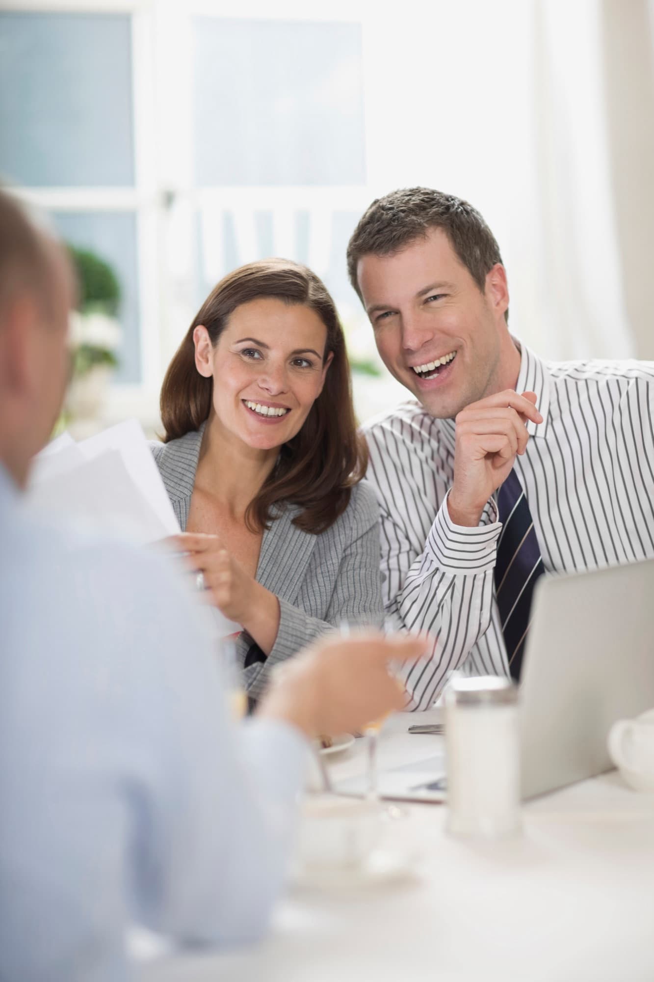 A smiling couple meeting with their lawyer to go over paperwork