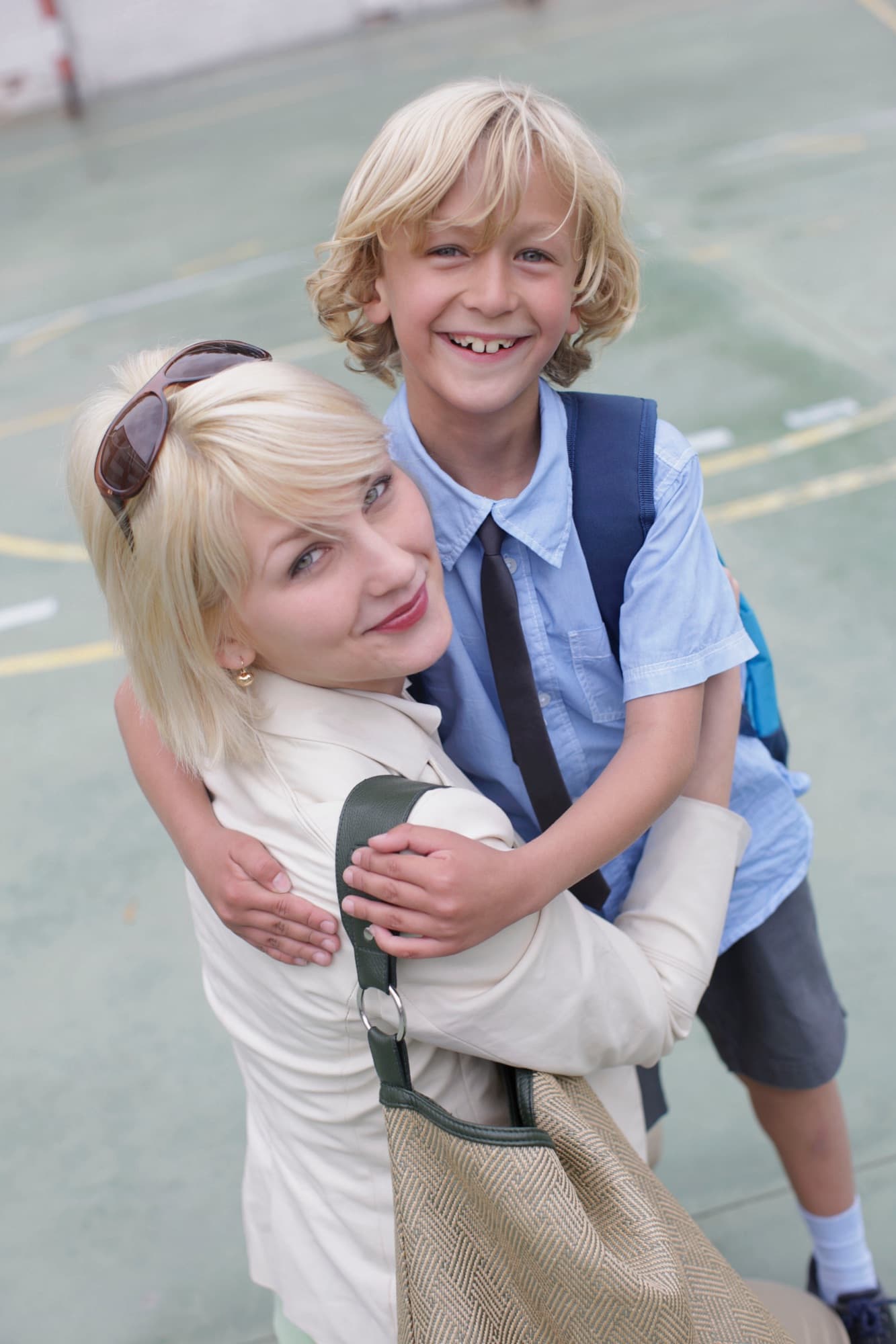 A smiling mother and her son hugging in a school playground